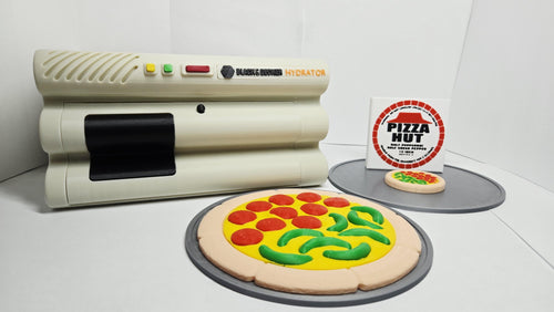Full-scale 3D printed Back to the Future hydrator prop with the dehydrated pizza disk and fully hydrated pizza displayed in front