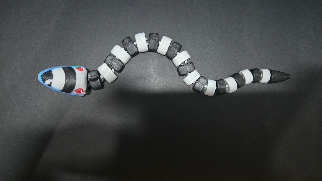 Beetlejuice sandworm flexi figure posed in a coiled position on a dark studio surface