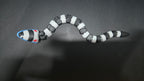 Beetlejuice sandworm flexi figure posed in a coiled position on a dark studio surface