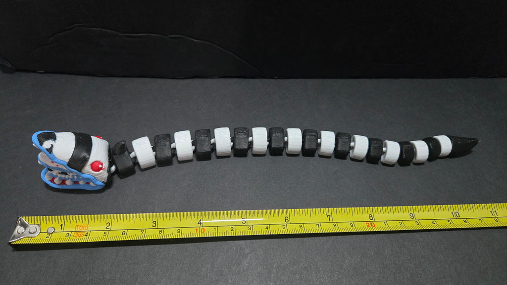 Beetlejuice sandworm flexi figure laid out straight next to a yellow measuring tape to show its length