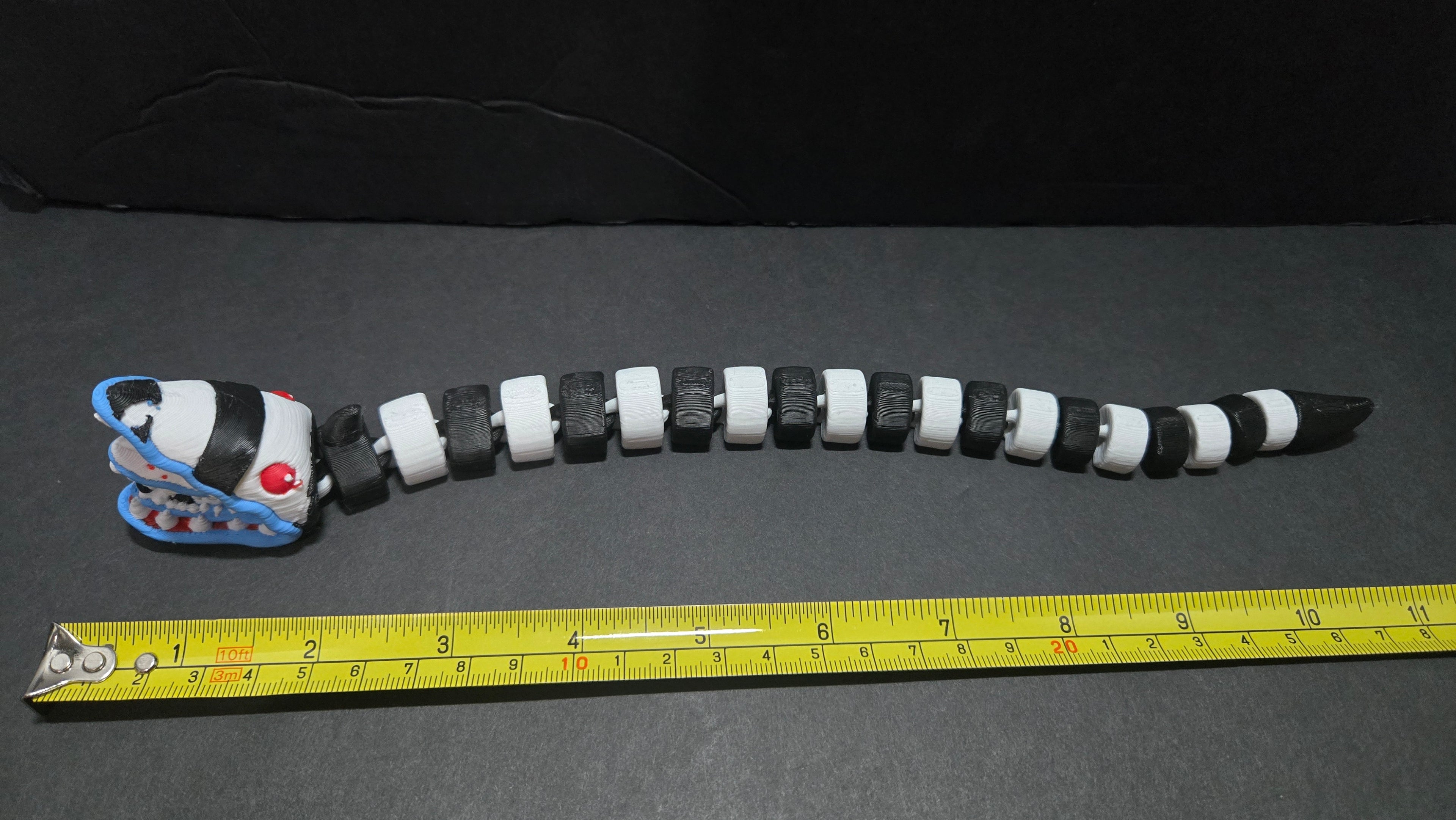 Beetlejuice sandworm flexi figure laid out straight next to a yellow measuring tape to show its length