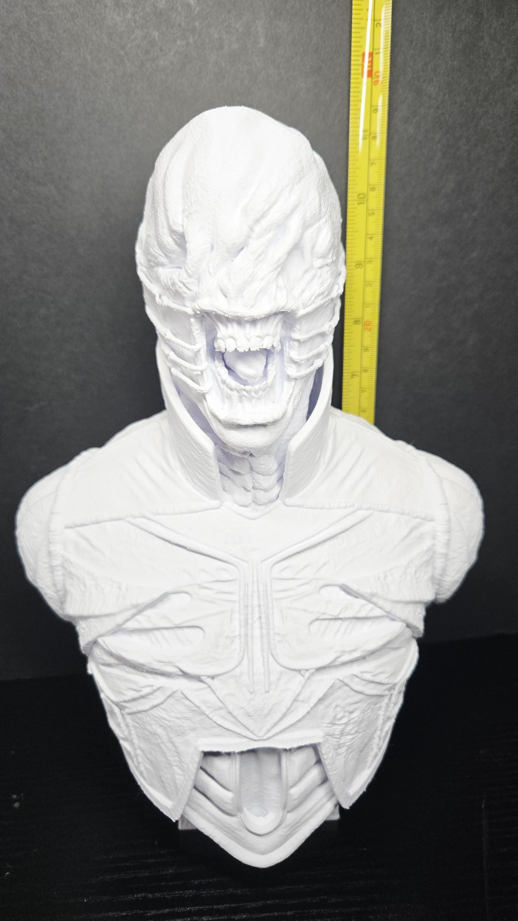 A vertical yellow measuring tape placed alongside the Chatterer Cenobite bust to demonstrate its physical height