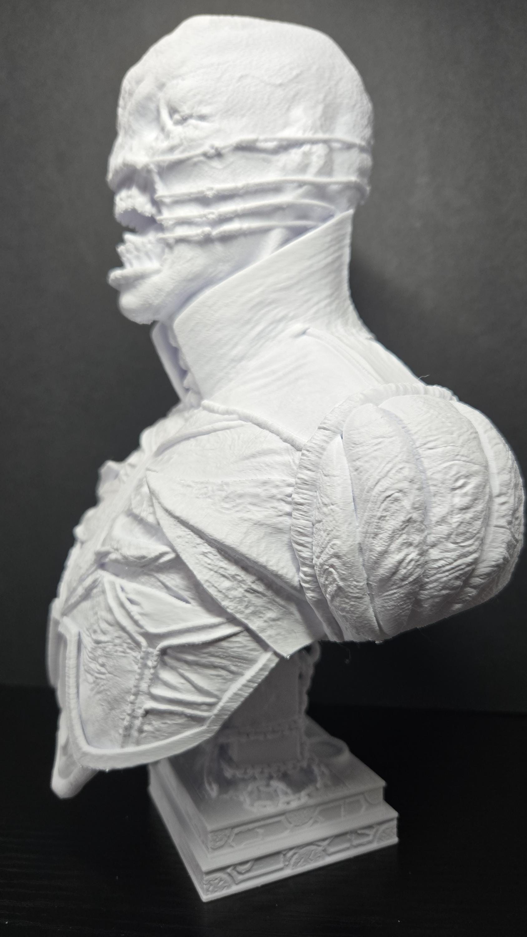 Three-quarter left profile view of the unpainted Chatterer bust showcasing the stitched jawline and shoulder plate detail
