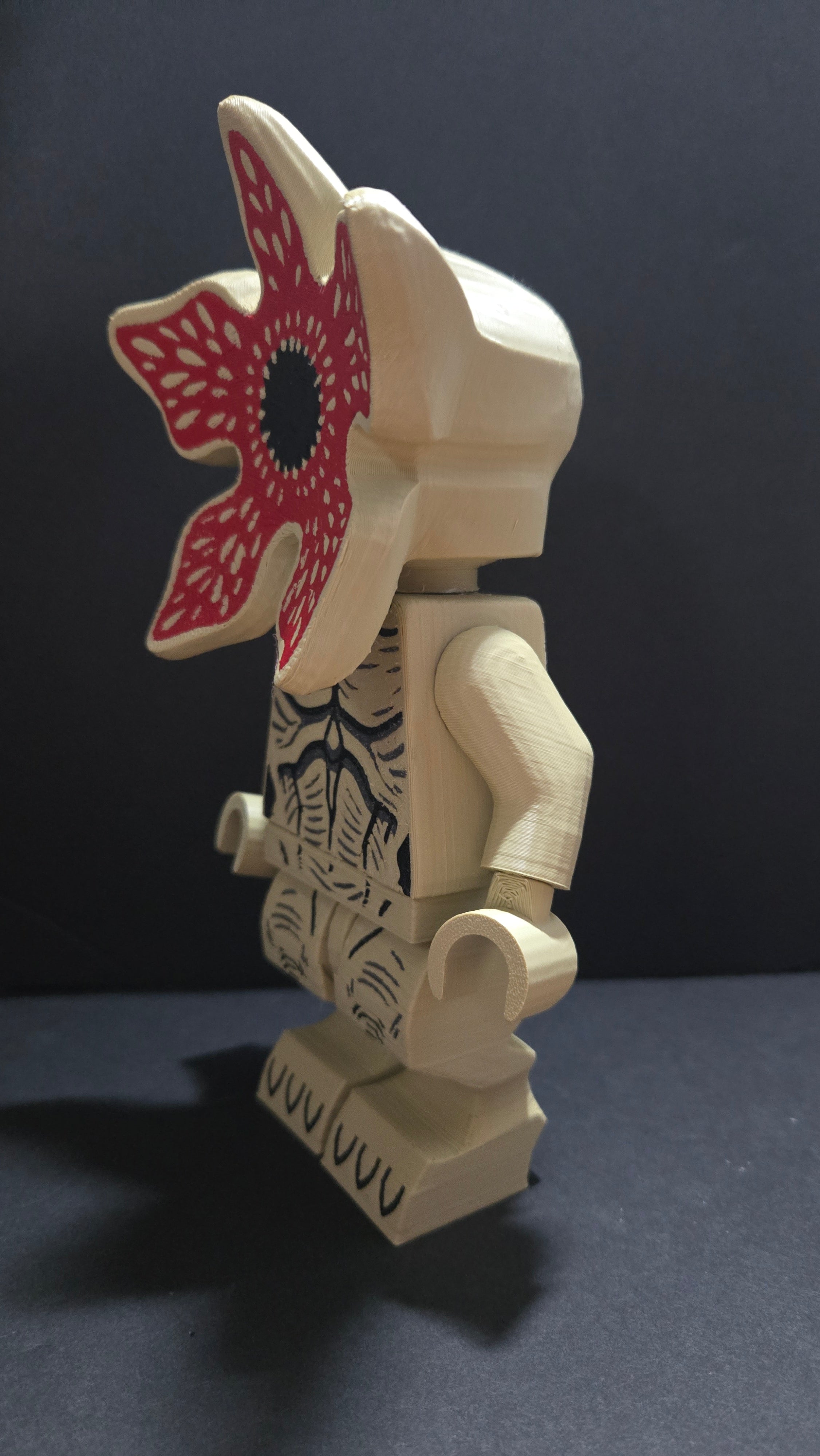 Left side profile view of the Demogorgon brick megafig standing on a dark studio surface