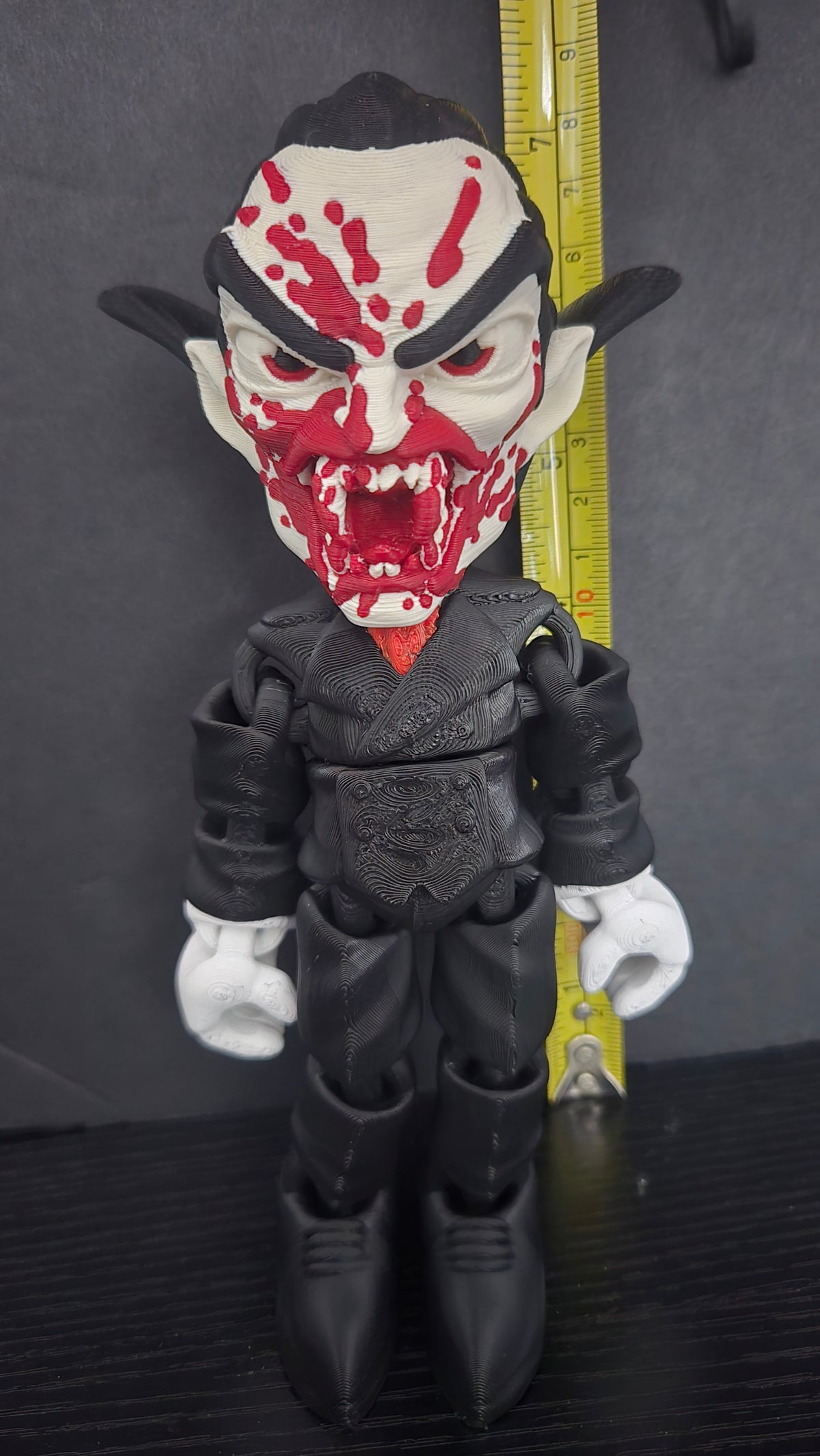 Dracula flexi figure standing next to a yellow measuring tape to display its 7.5-inch height
