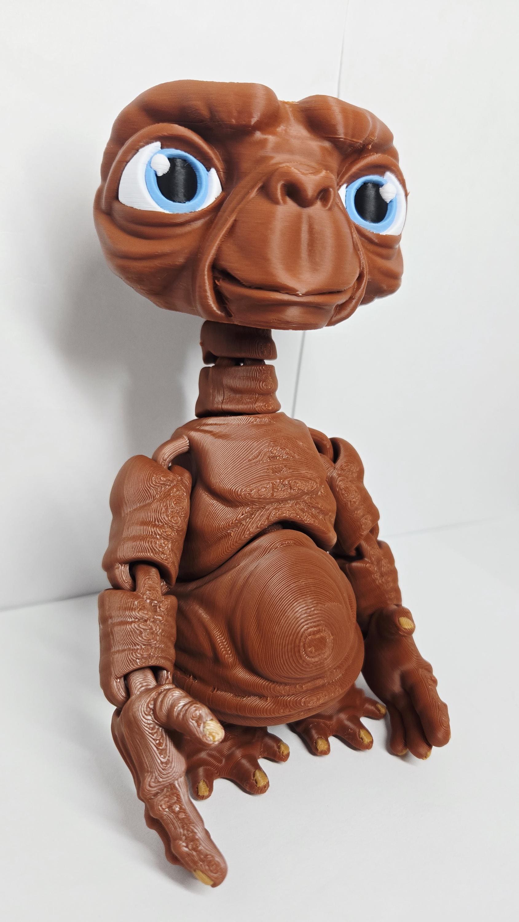 The 3D printed E.T. flexi figure displayed standing upright on a restaurant table next to a pizza and drink