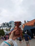 Person holding the 3D printed E.T. flexi figure in their hand with the E.T. Adventure theme park entrance in the background