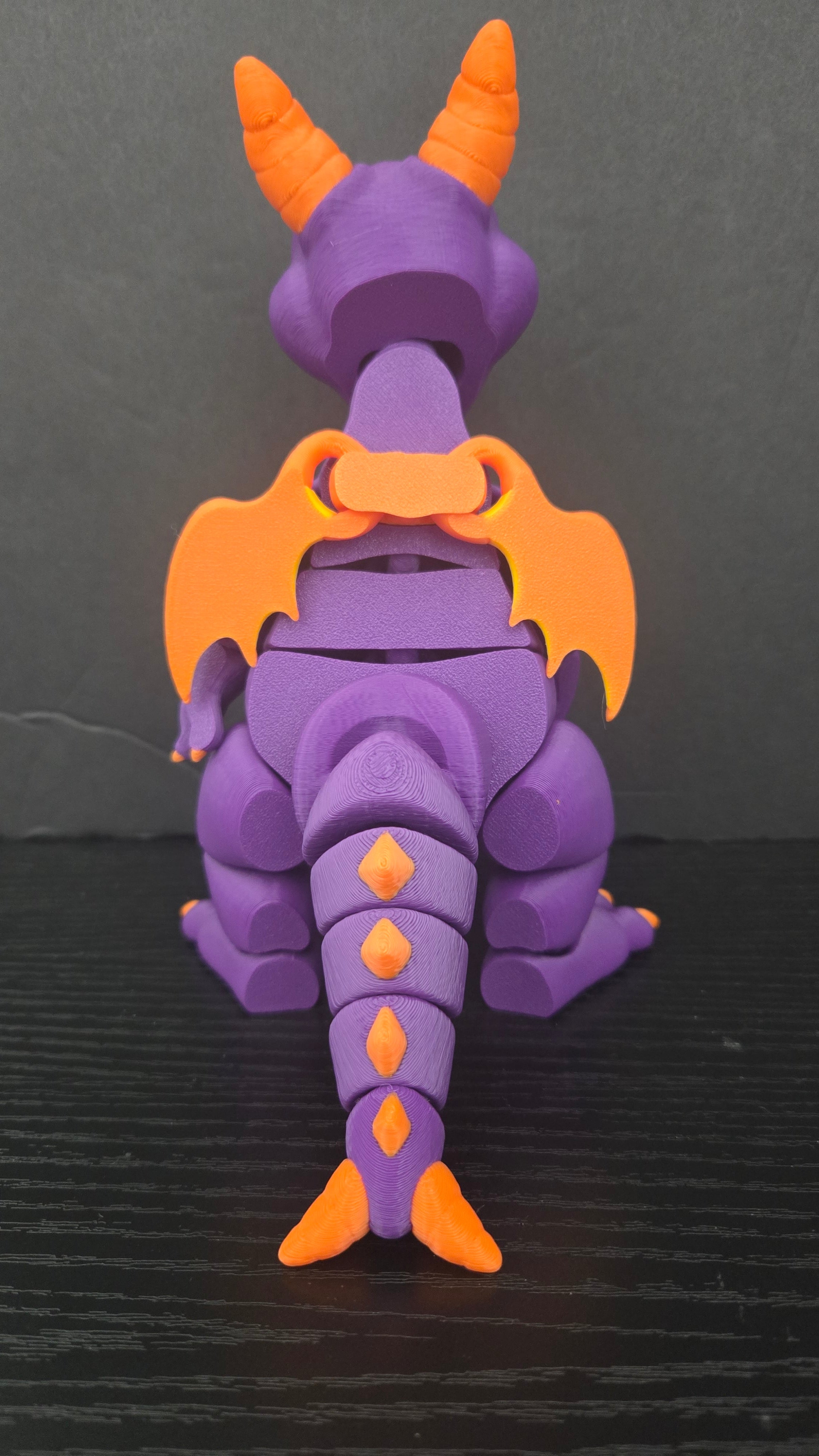 Rear view of the Figment flexi figure displaying its orange wings, back spikes, and segmented tail