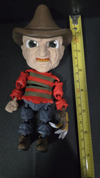Straight front view highlighting the size of the fedora hat and iconic striped sweater on the flexible Freddy Krueger toy