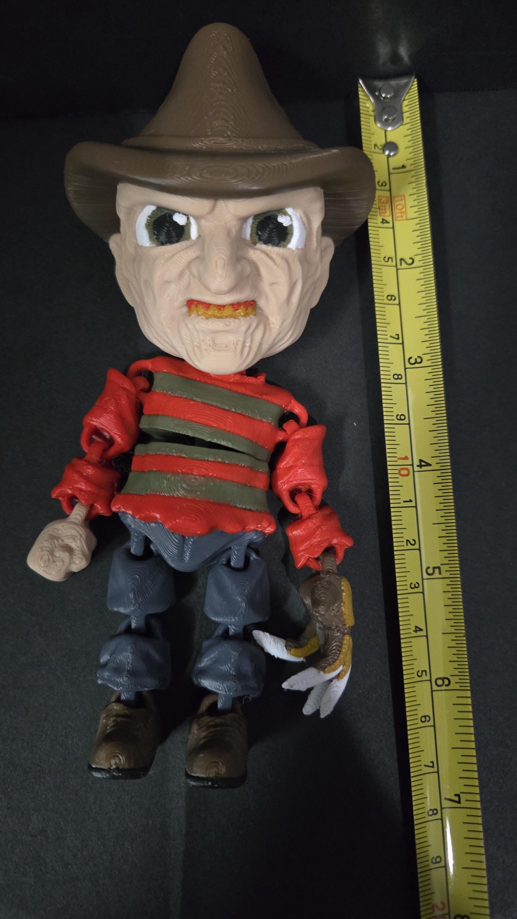 Straight front view highlighting the size of the fedora hat and iconic striped sweater on the flexible Freddy Krueger toy
