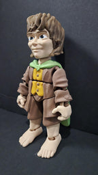 Left side profile view of the flexible Frodo Baggins toy showing the shoulder cloak drape and arm articulation joints