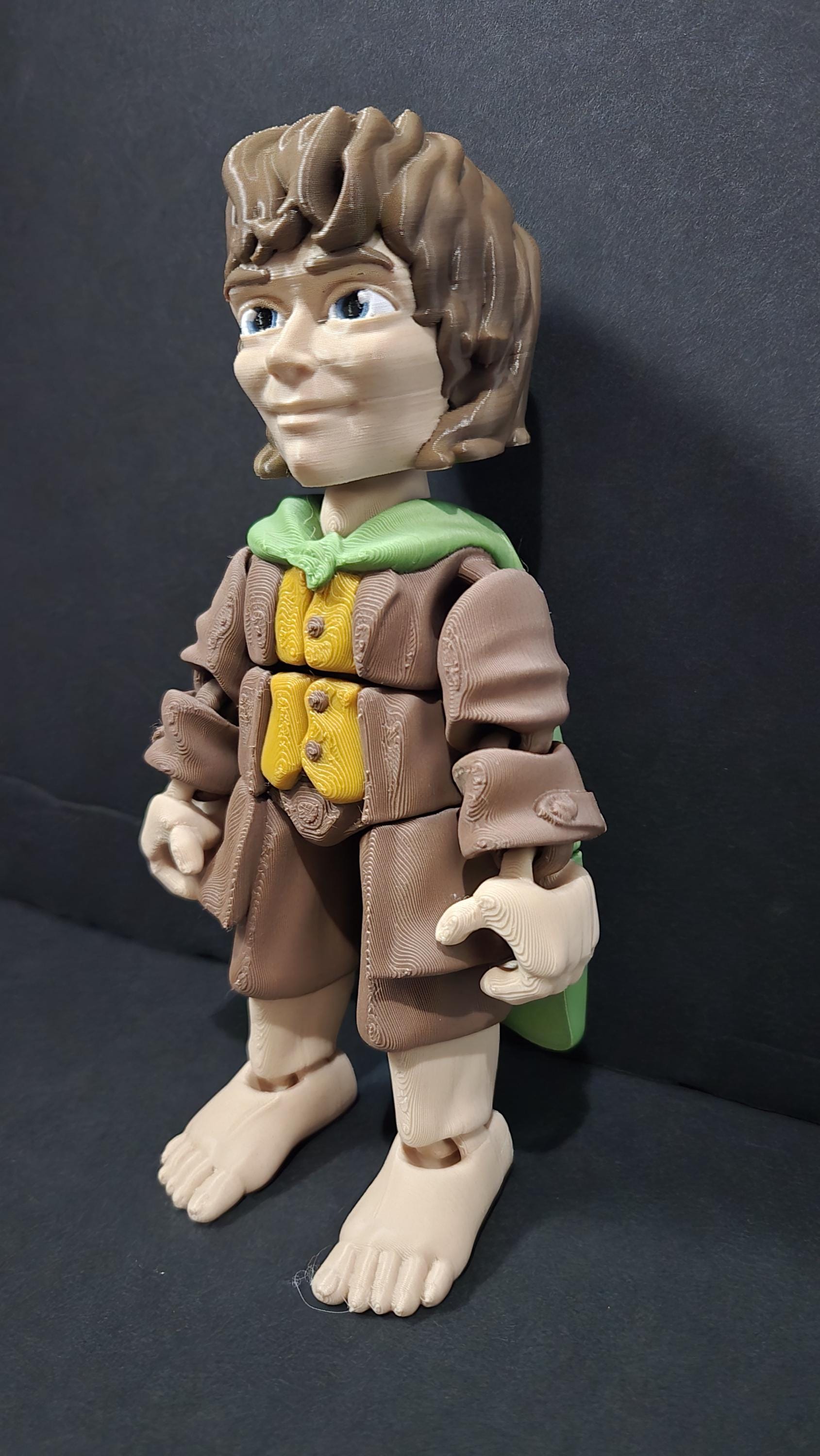 Left side profile view of the flexible Frodo Baggins toy showing the shoulder cloak drape and arm articulation joints