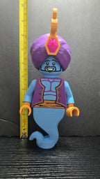 Genie brick megafig standing next to a yellow measuring tape to display its 10-inch height