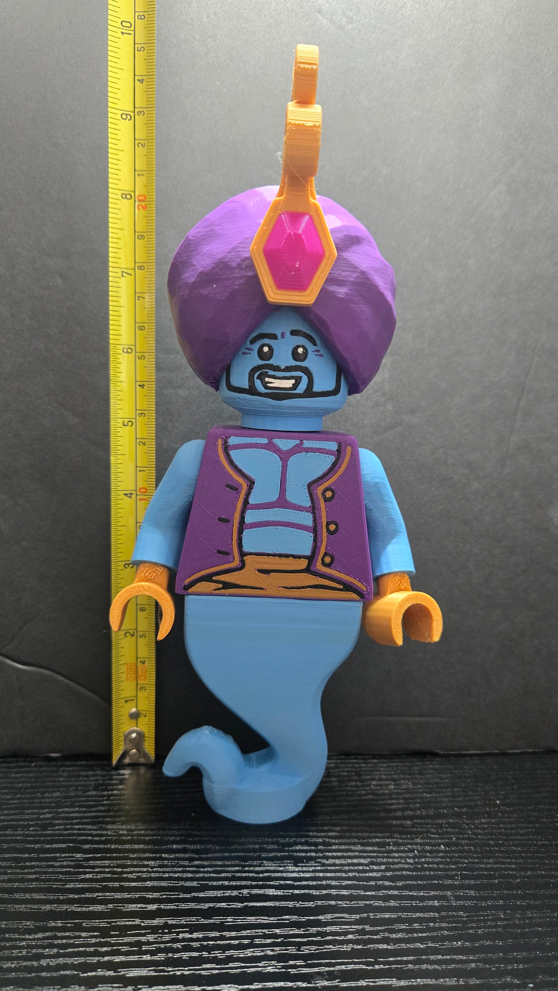 Genie brick megafig standing next to a yellow measuring tape to display its 10-inch height