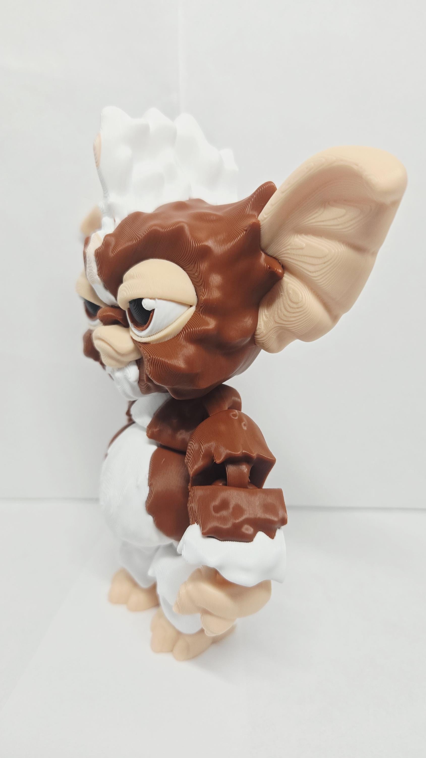 Left side profile view of the flexible Gizmo toy showing the ear width, round head profile, and arm articulation joints