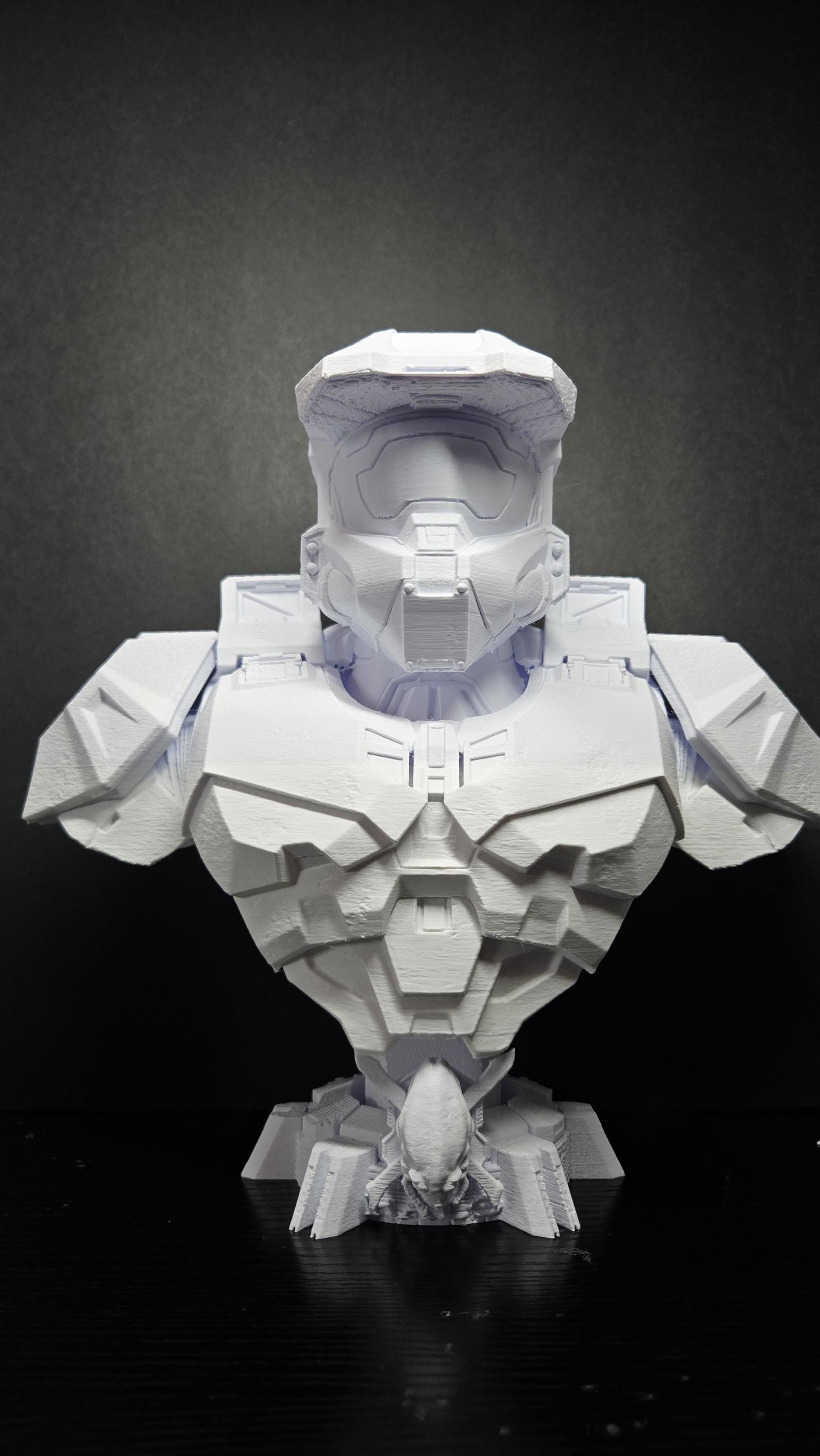 Unpainted white 3D printed Master Chief bust from Halo standing fully assembled on a black tabletop showing a complete front view