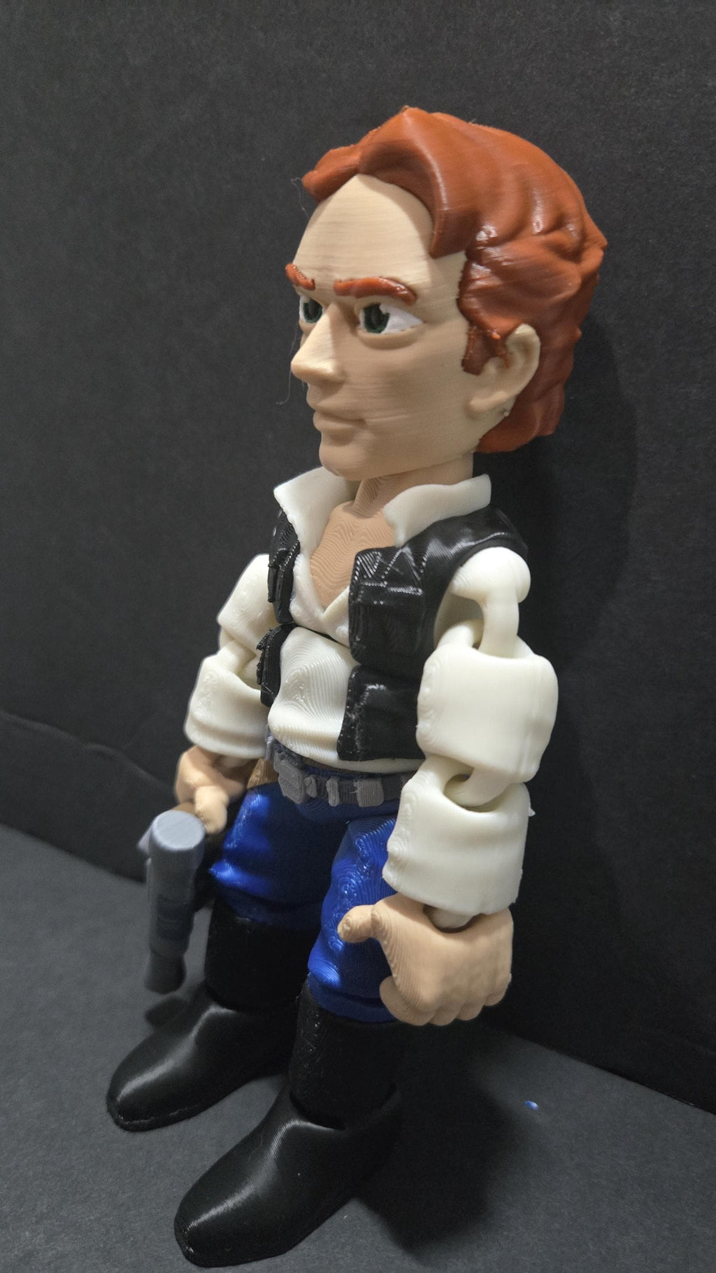 Three-quarter right side profile view of the flexible Han Solo figure showcasing his black vest, brown hair, and side-mounted holster