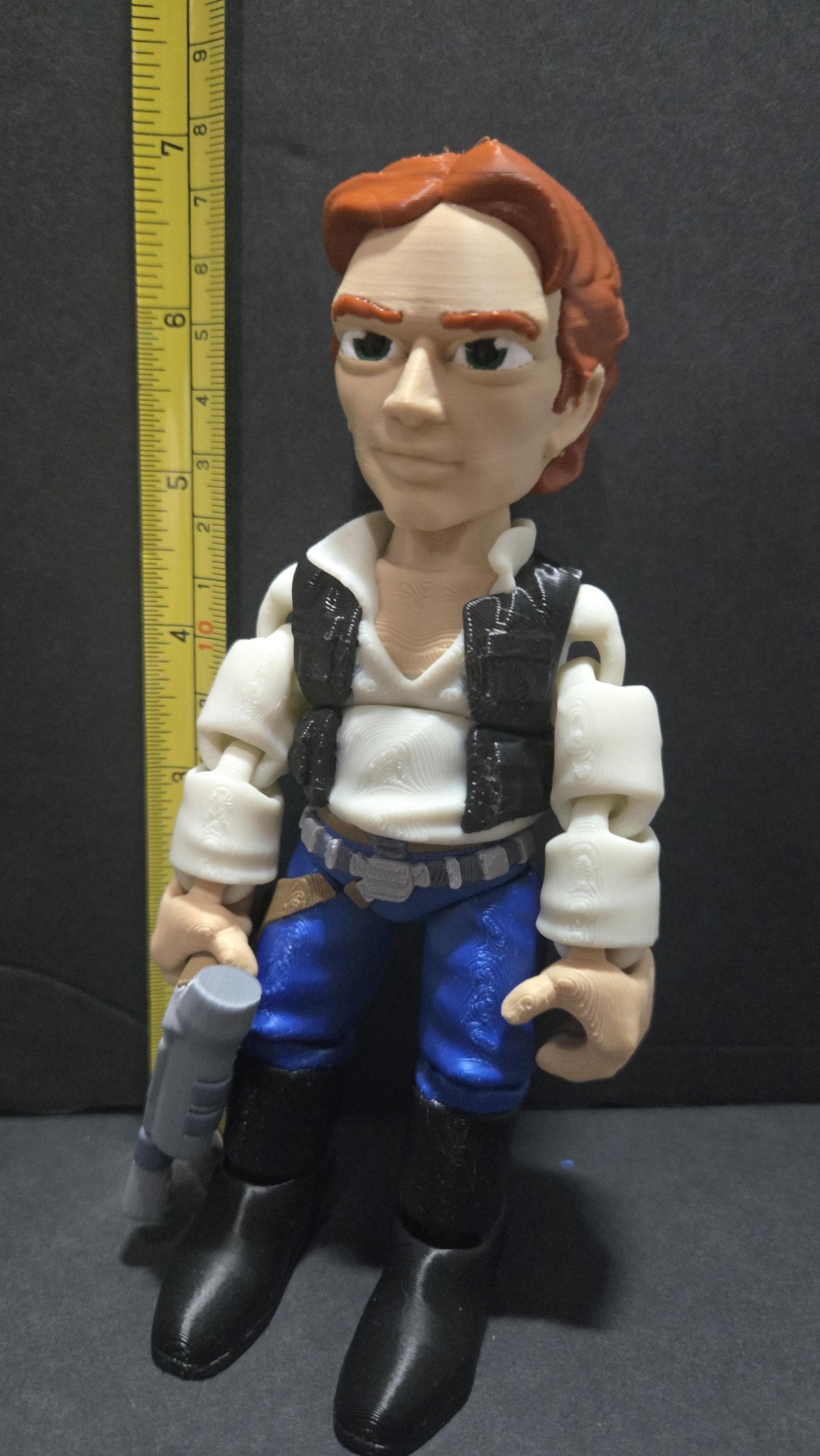 A vertical yellow measuring tape placed alongside the standing multi-color Han Solo flexi figure to display its exact physical height