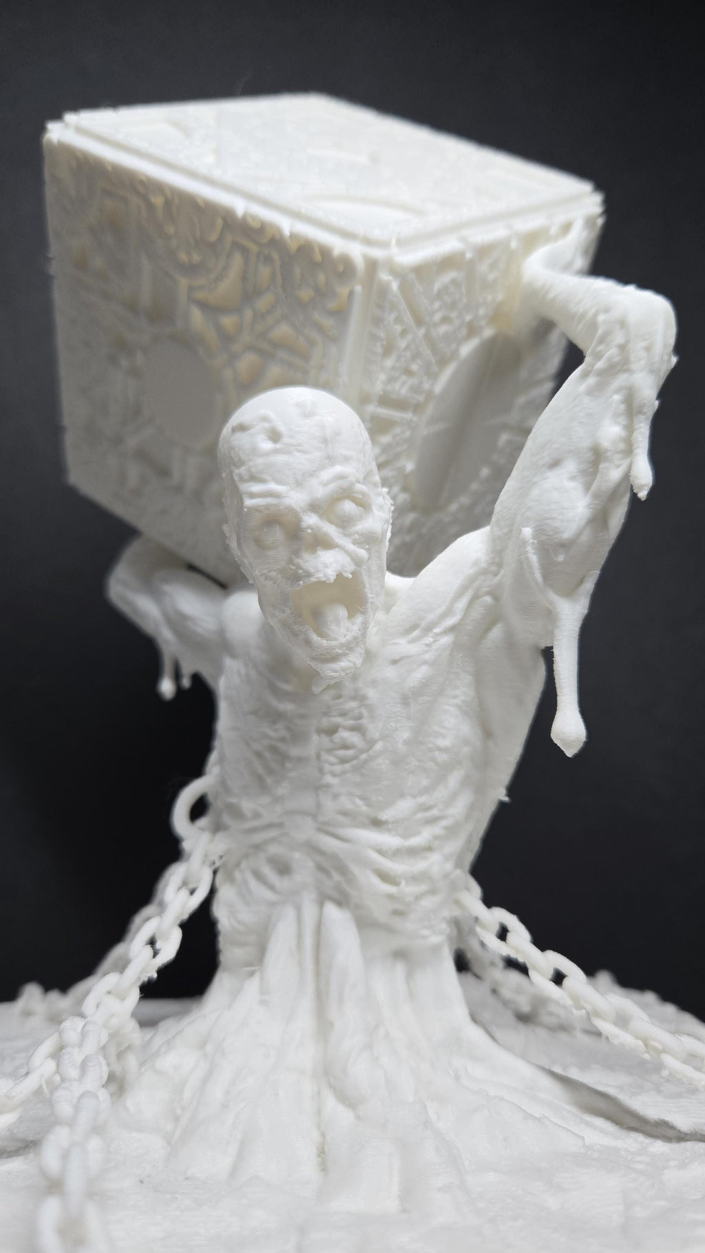 Close-up of the unpainted 3D printed figure holding the detailed puzzle box above its head