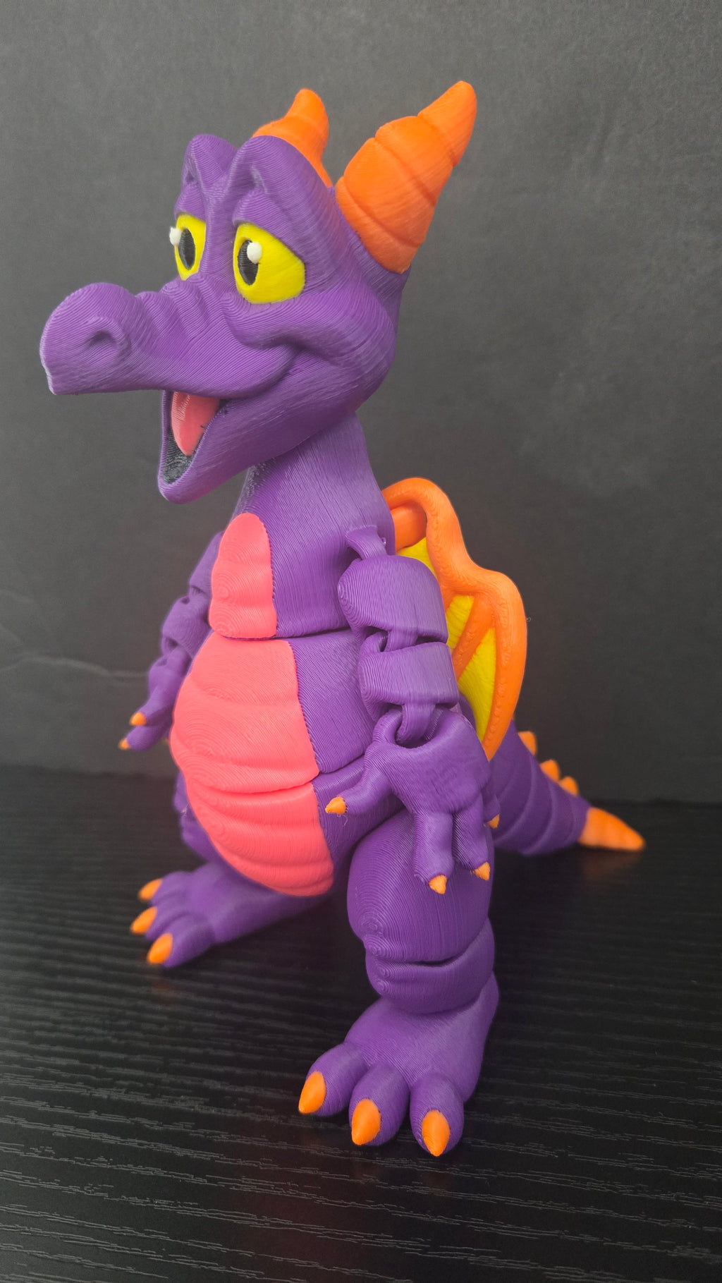 Angled side view of the Figment dragon figure highlighting its horns, smiling face, and posable arms