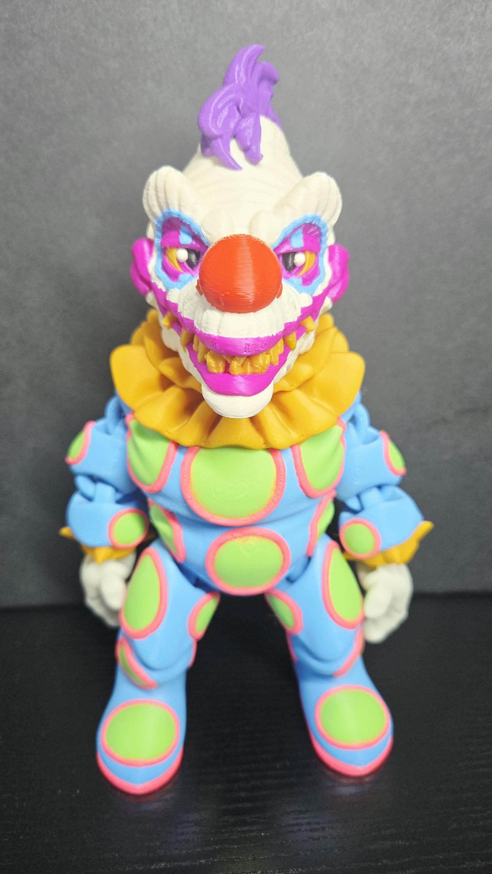 Straight front view of the 3D printed Klownzilla flexi figure showing his vibrant neon-spotted suit