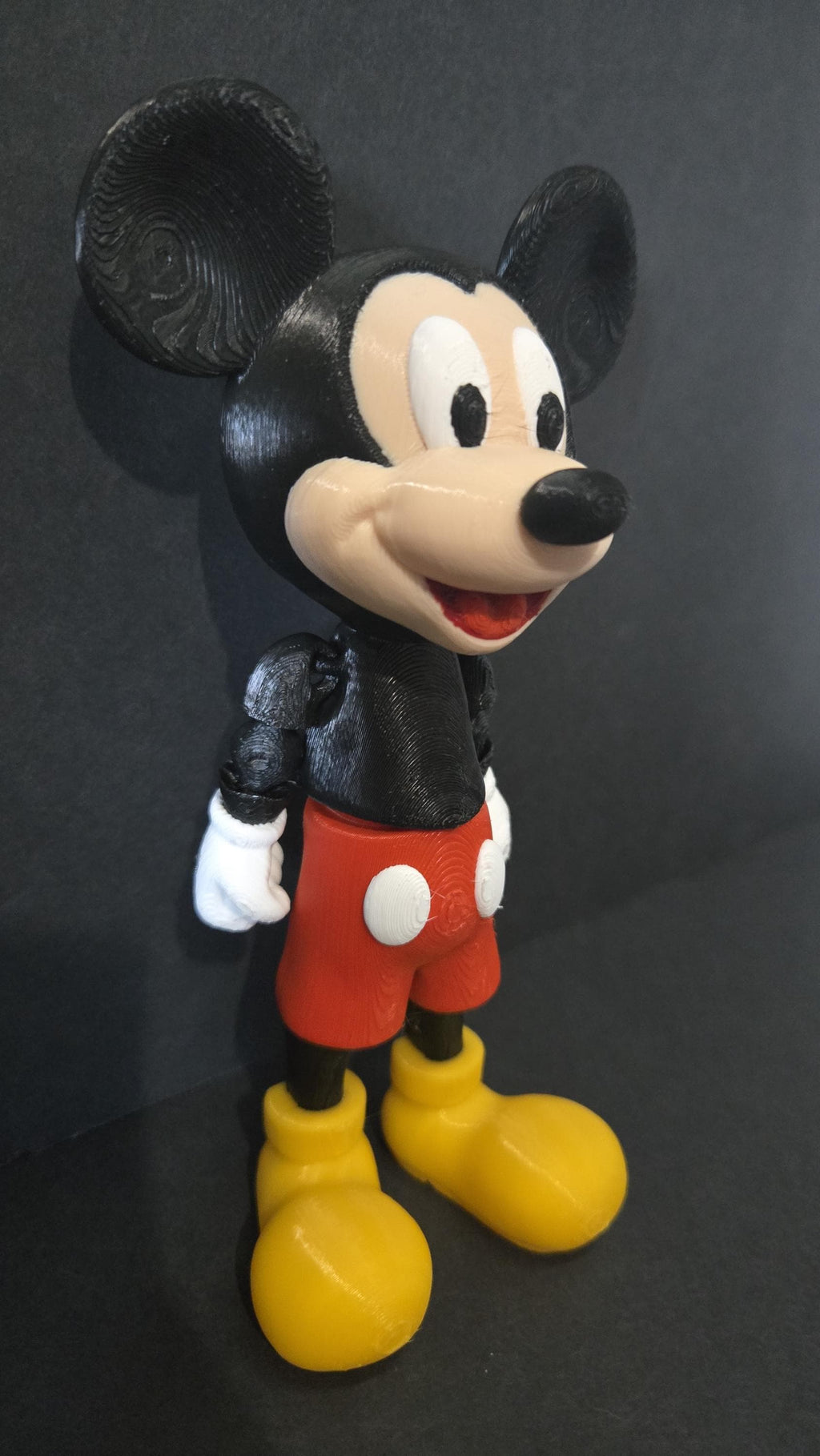 Side profile view of the flexible Mickey Mouse figure showing the ear shape, shorts, and arm articulation joints