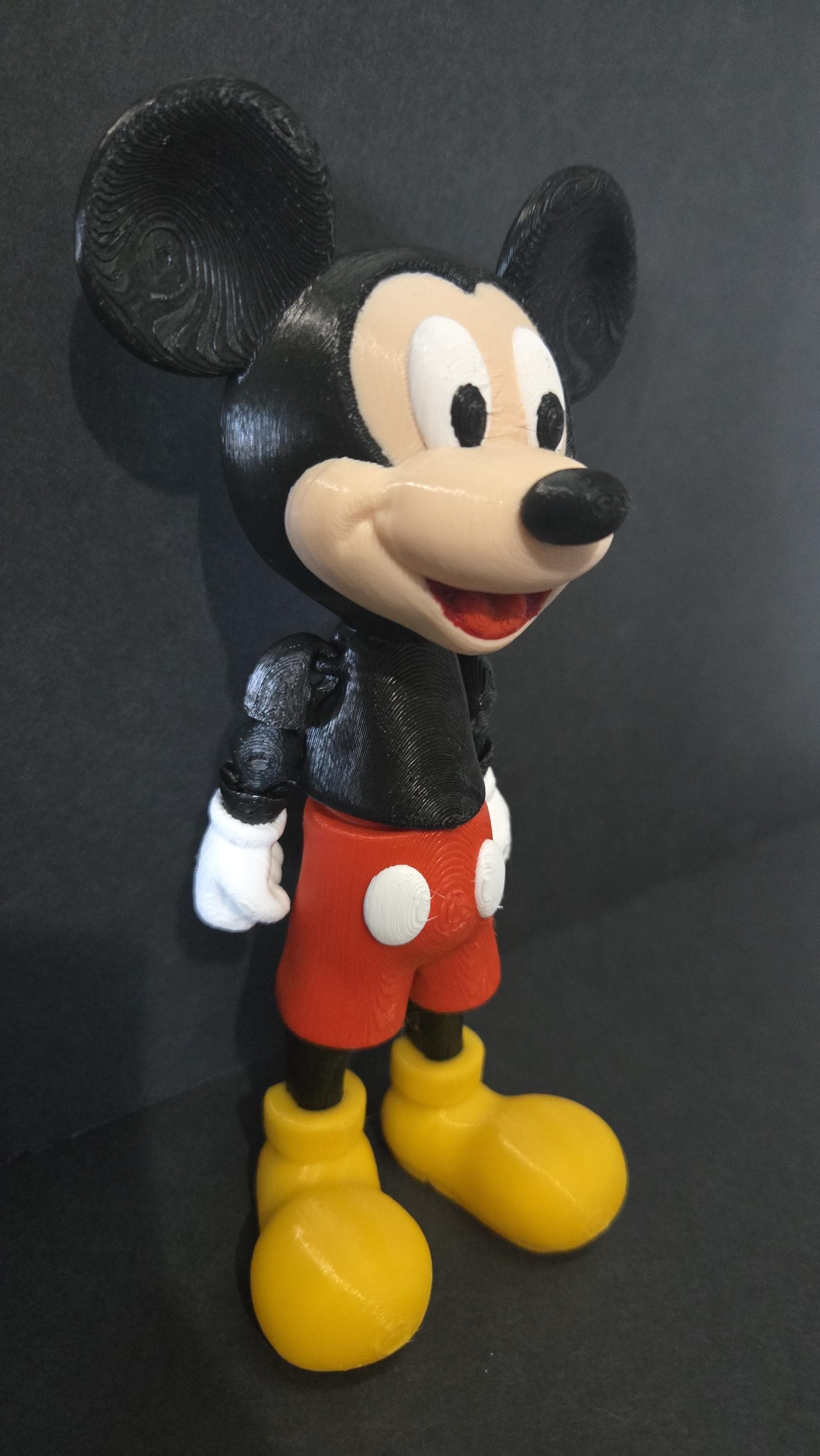 Side profile view of the flexible Mickey Mouse figure showing the ear shape, shorts, and arm articulation joints