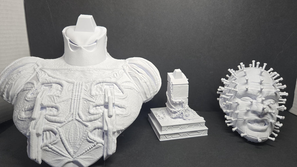 The 3D printed Pinhead bust disassembled into its three interlocking parts showing the torso, connector block, and head specimen