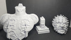 The 3D printed Pinhead bust disassembled into its three interlocking parts showing the torso, connector block, and head specimen