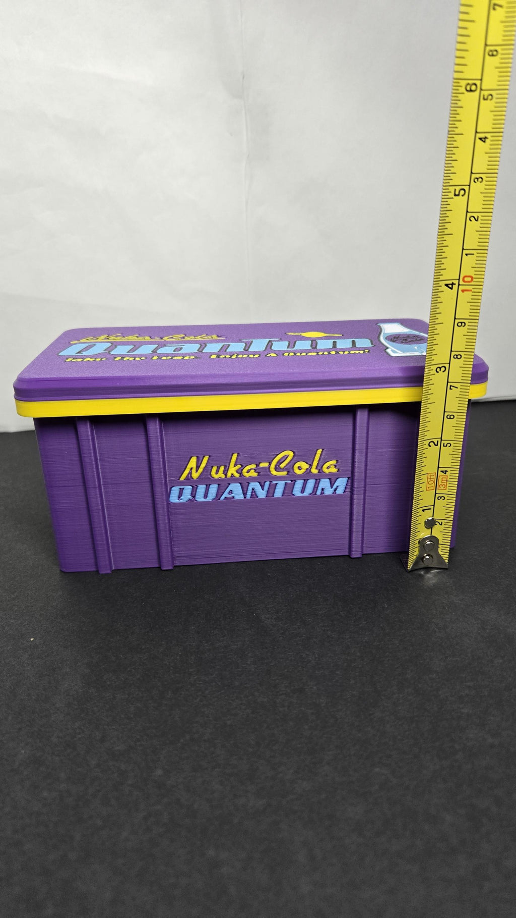 A vertical yellow measuring tape placed alongside the closed storage box to display its exact physical height