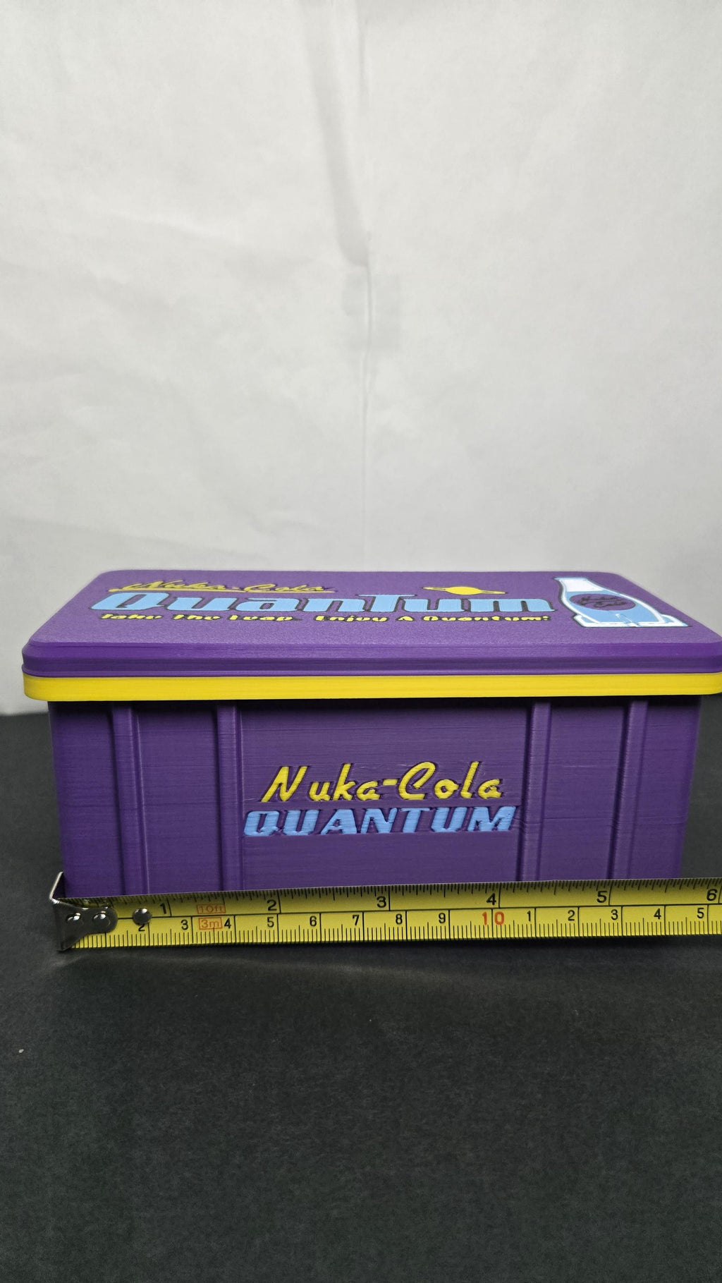 A horizontal yellow measuring tape placed across the closed storage box to display its exact physical width