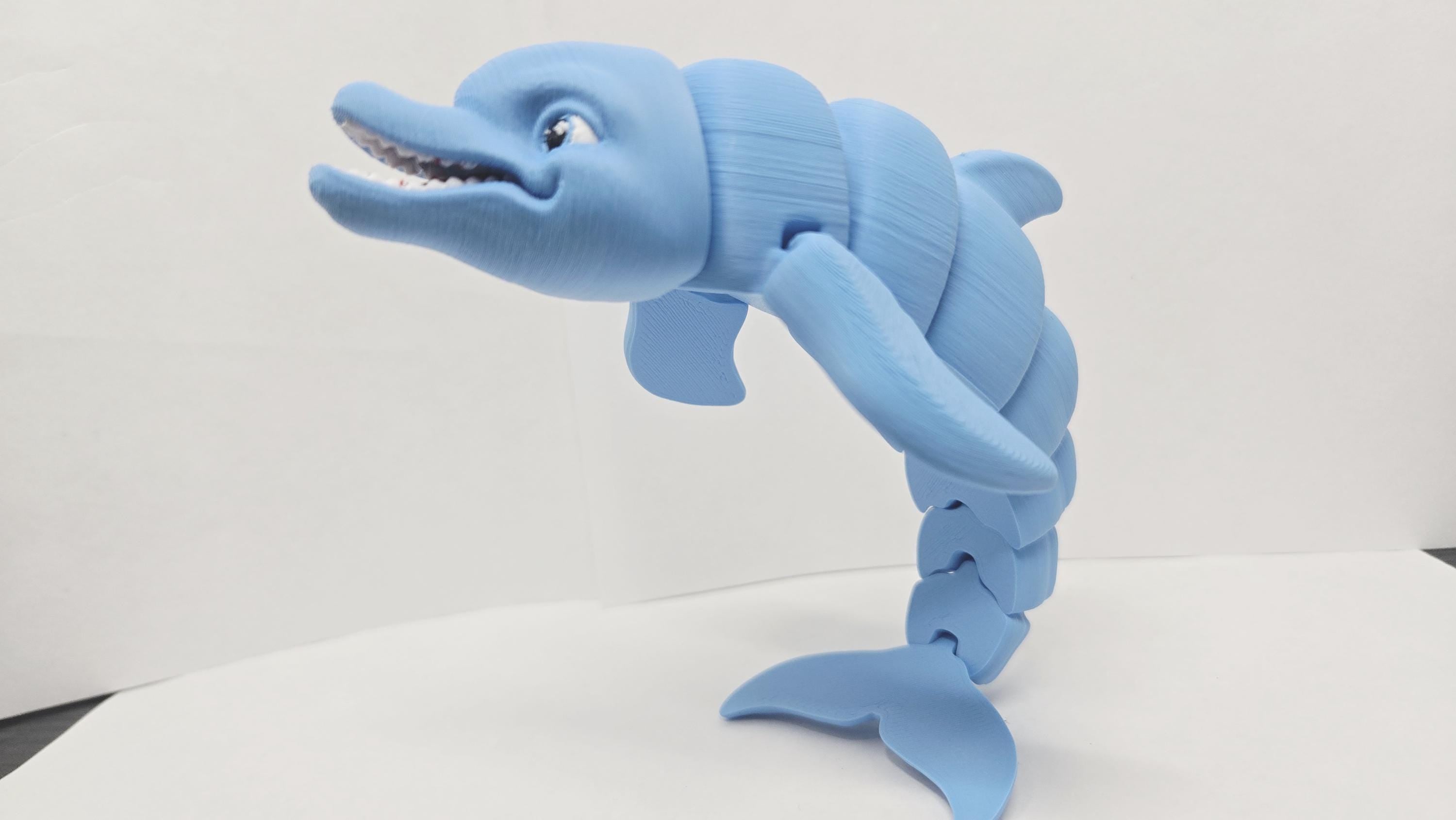 Angled view of the 3D printed dolphin figurine showcasing the clean jointed interlocking segments and prominent dorsal fin along its back