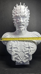 A horizontal yellow measuring tape placed across the shoulders of the unpainted Cenobite bust to show the exact physical width