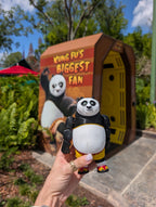Close-up shot of the flexible Po panda figurine being held in the air at Universal Studios, showcasing its vibrant full-color details in natural sunlight