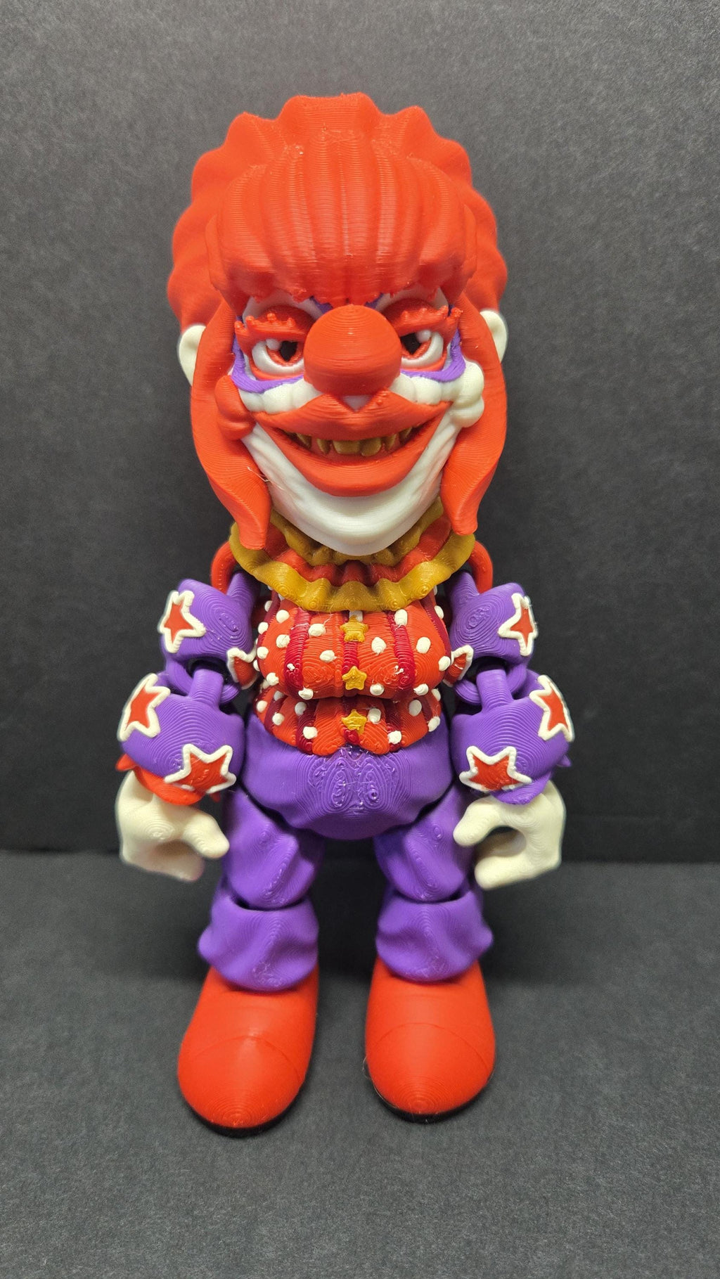 Straight front view of the 3D printed Rosebud flexi figure showing his orange hair and patterned clown suit