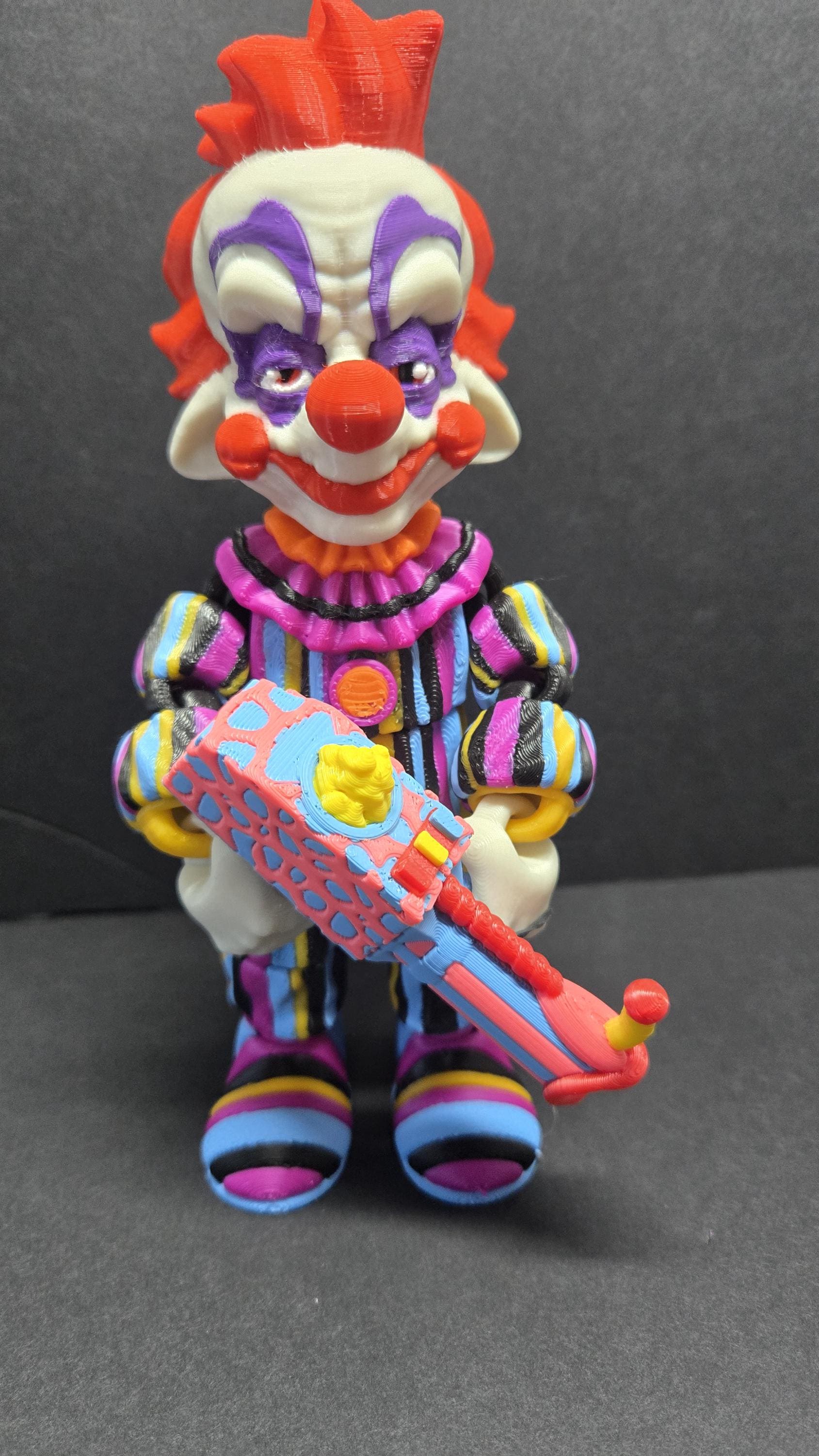 Straight front view of the 3D printed Rudy flexi figure posed holding his colorful popcorn gun