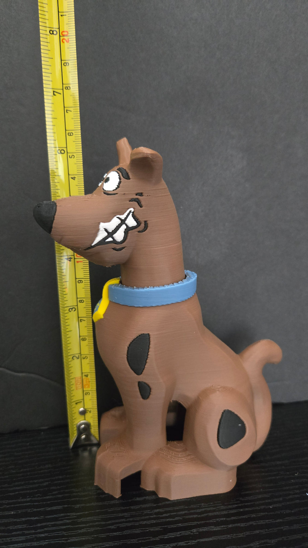 Scooby-Doo brick megafig standing next to a yellow measuring tape to display its 6.5-inch height