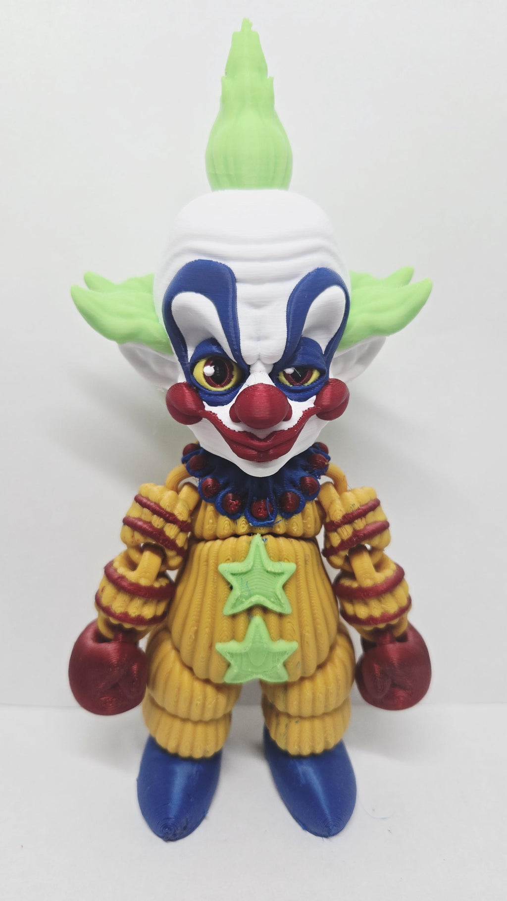 Straight front view of the 3D printed Shorty flexi figure showing his green hair and patterned clown suit