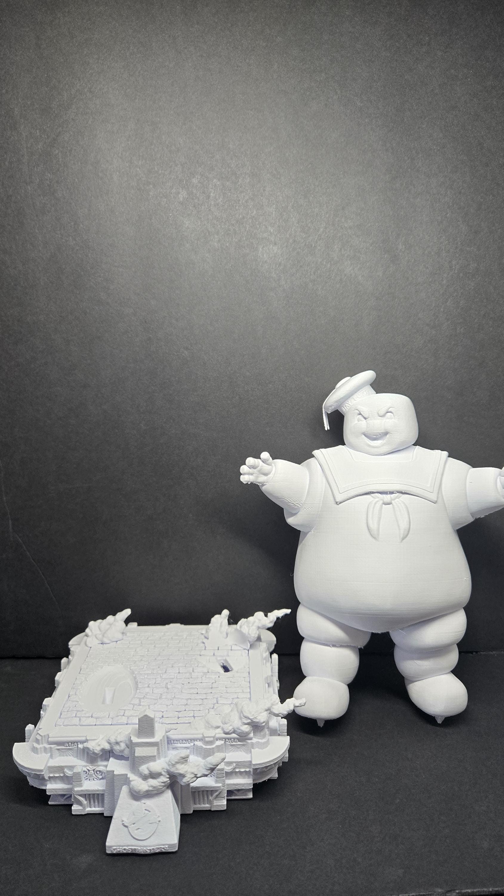 The 3D printed Stay Puft Marshmallow Man diorama disassembled into its modular parts, showing the giant figure separated from the detailed city street base