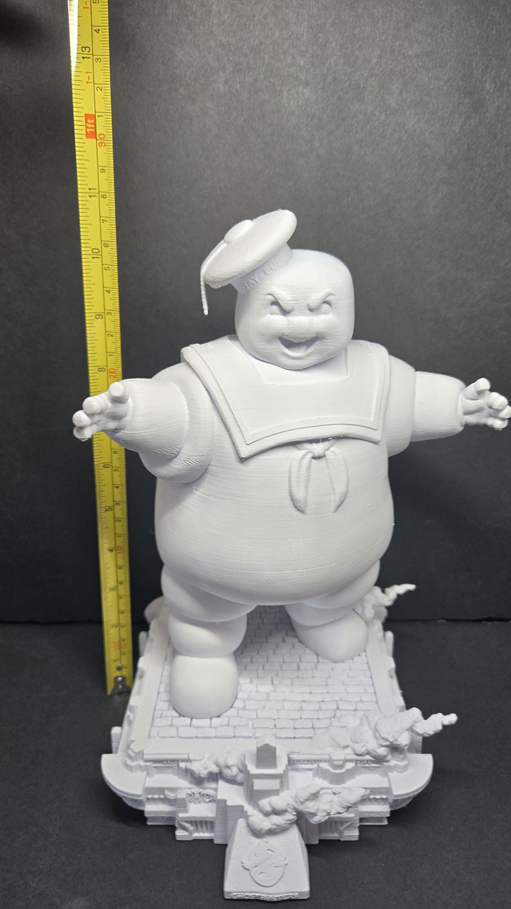 A vertical yellow measuring tape placed alongside the fully assembled Stay Puft diorama to display its exact physical height