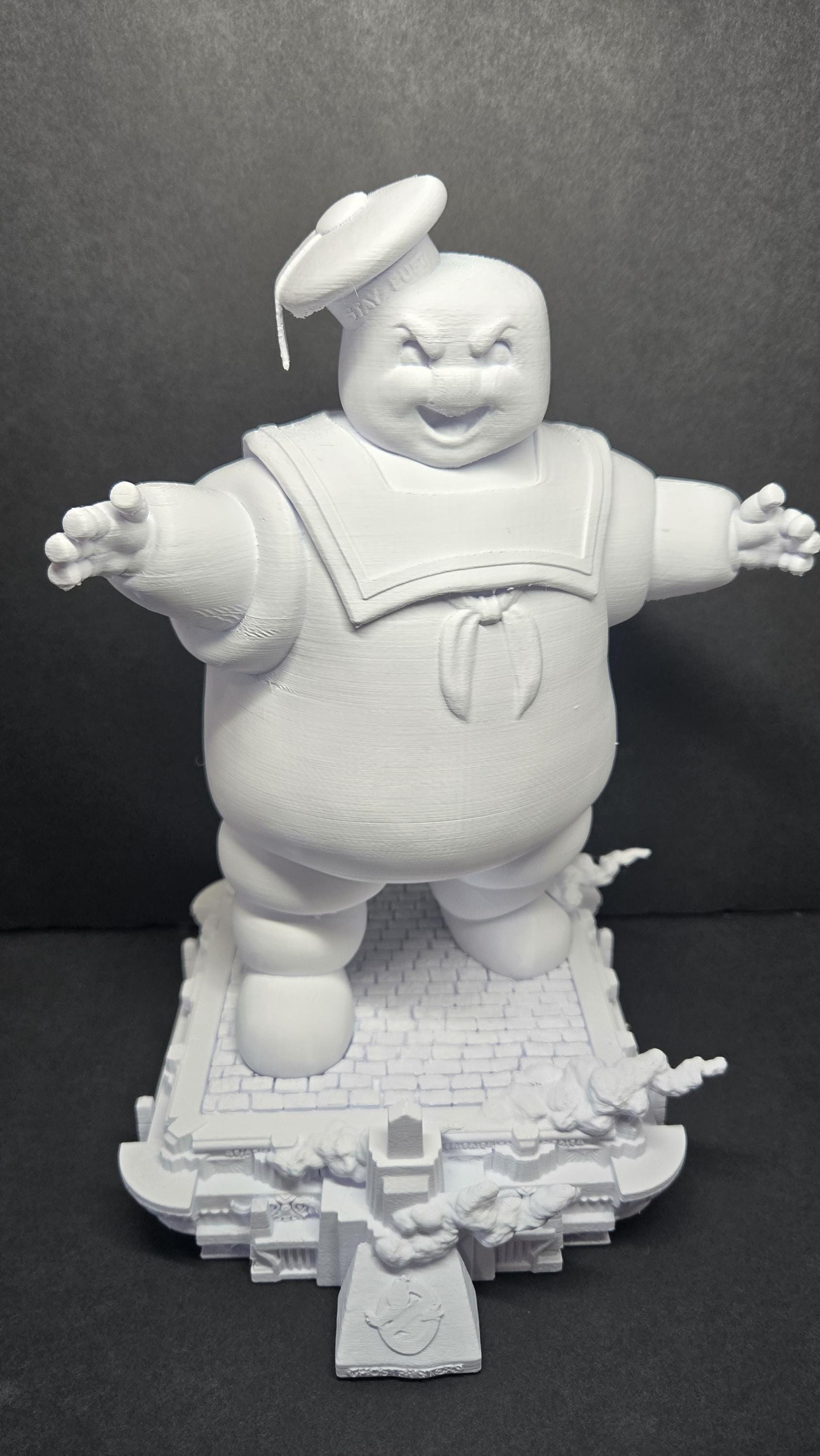 Straight front view of the unpainted 3D printed Stay Puft diorama on a black background showing the giant standing on a detailed city street base
