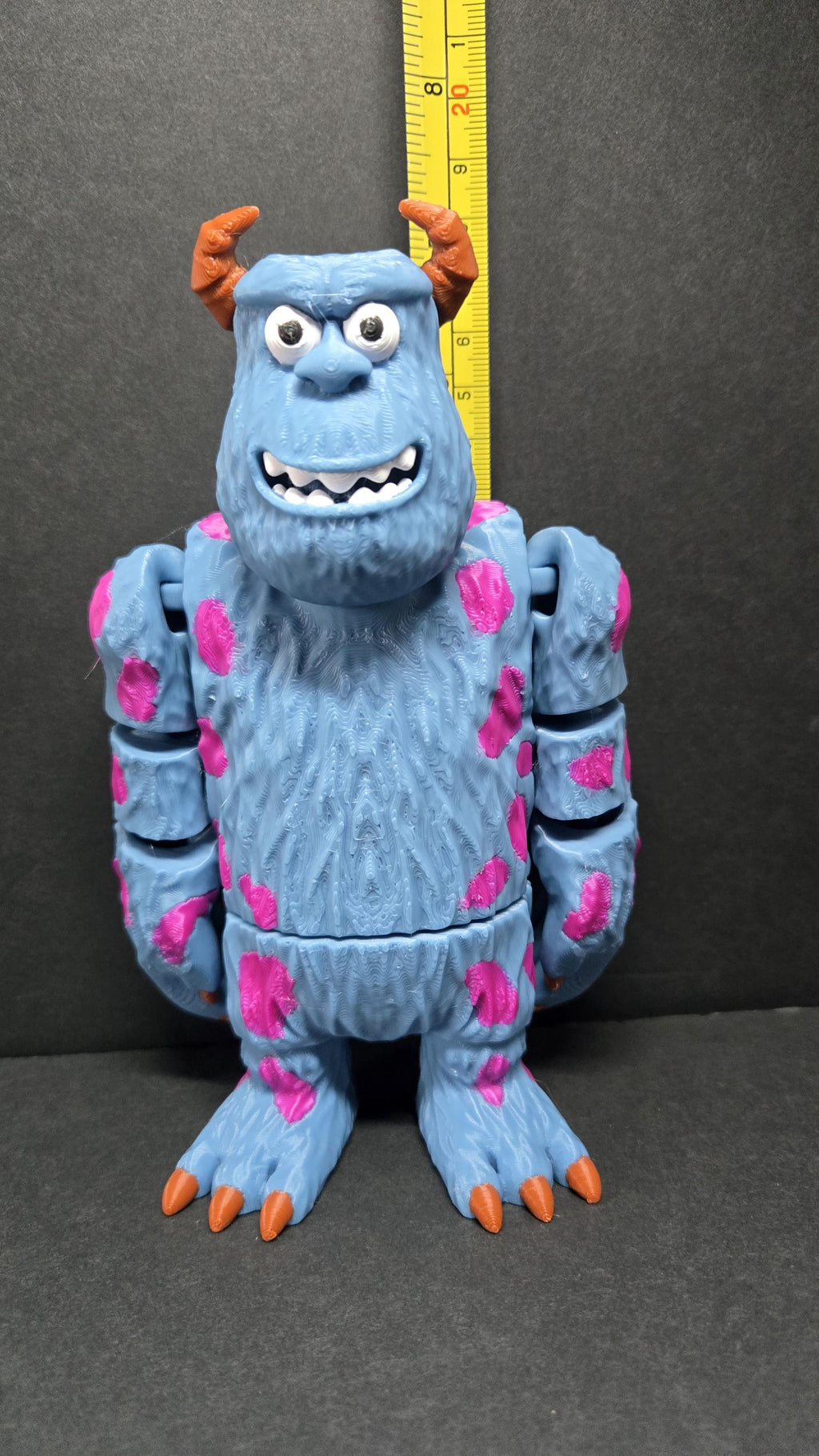 3D printed Sully flexi figure standing next to a measuring tape to demonstrate its display-friendly height
