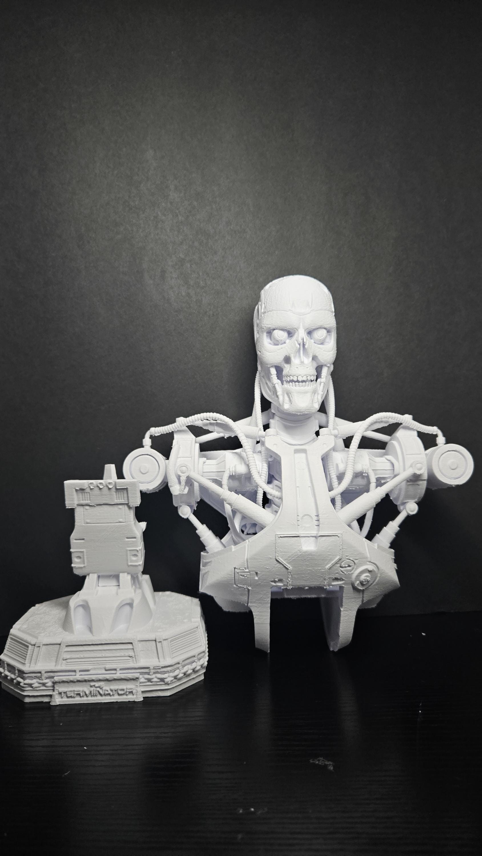 An 11-inch tall 3D printed T-800 cyborg bust standing on a desk to show its large physical scale