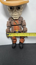 A horizontal yellow measuring tape placed across the arms of The Ghoul flexi figure to display its exact physical width