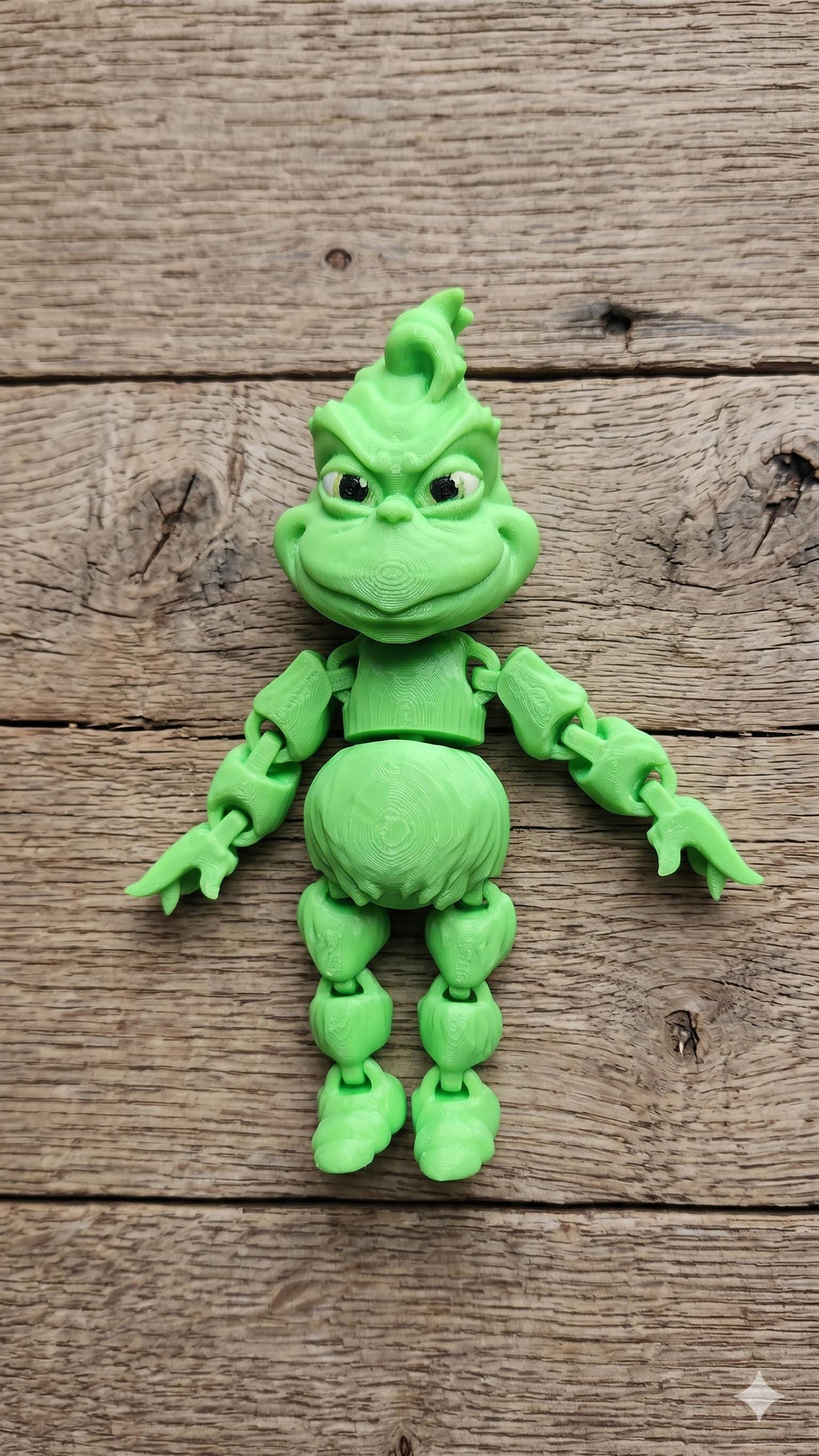 Full-color 3D printed grumpy holiday star flexi figure standing on a rustic wooden desk surface