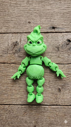 Full-color 3D printed grumpy holiday star flexi figure standing on a rustic wooden desk surface
