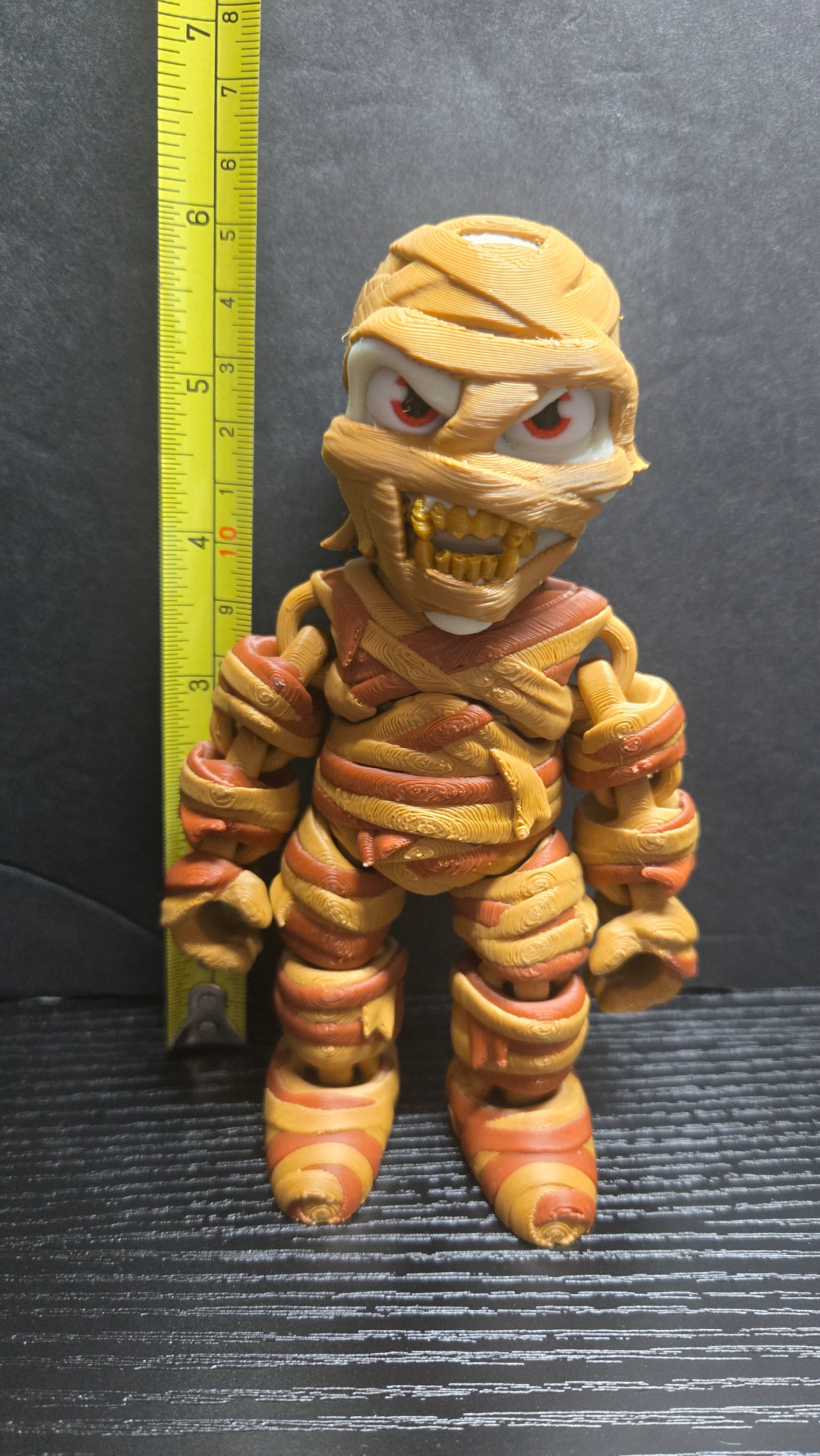 The Mummy flexi figure standing next to a yellow measuring tape to display its 6-inch height