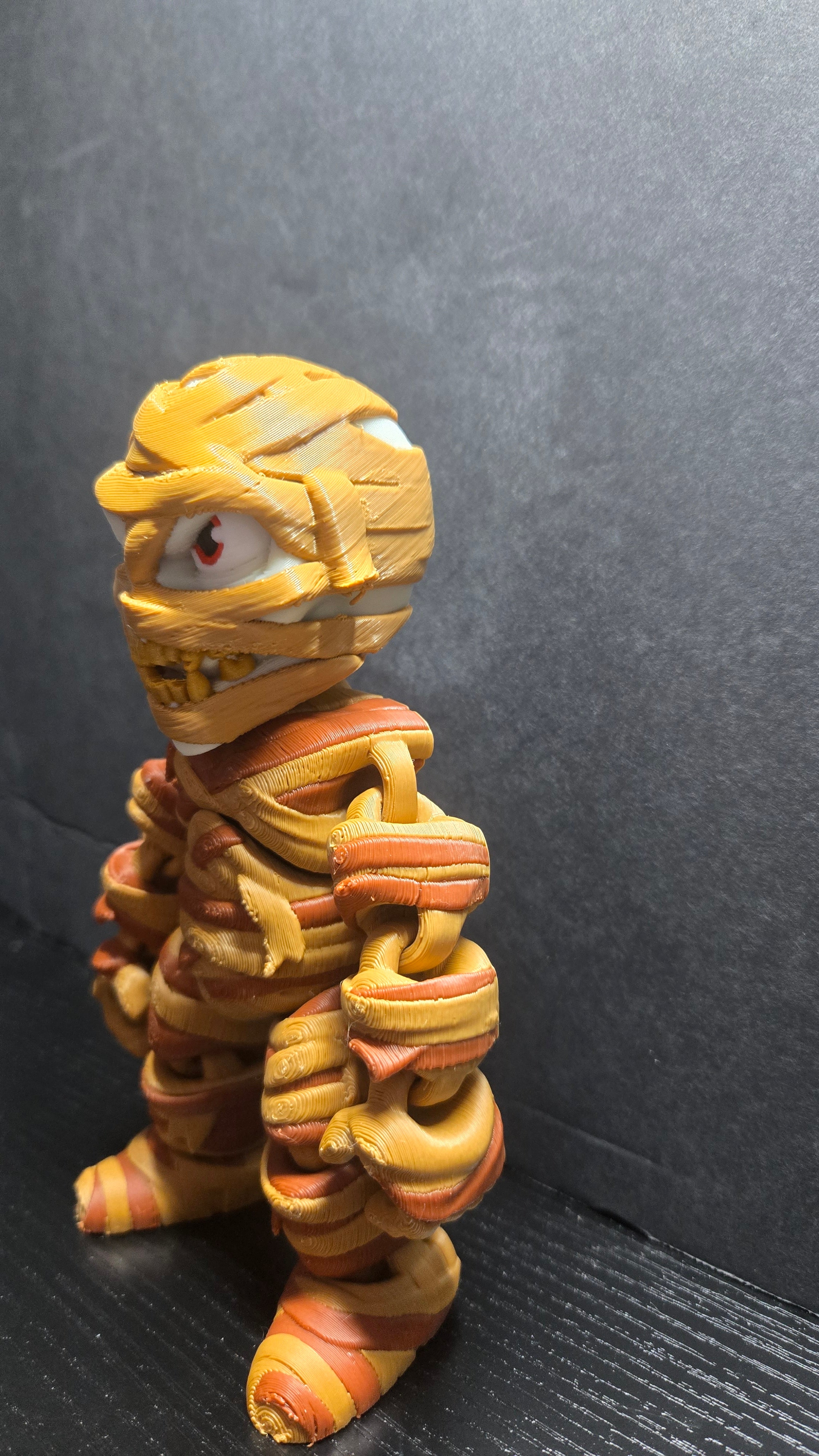 Left side profile view of the 6-inch Mummy flexi figure on a dark tabletop surface