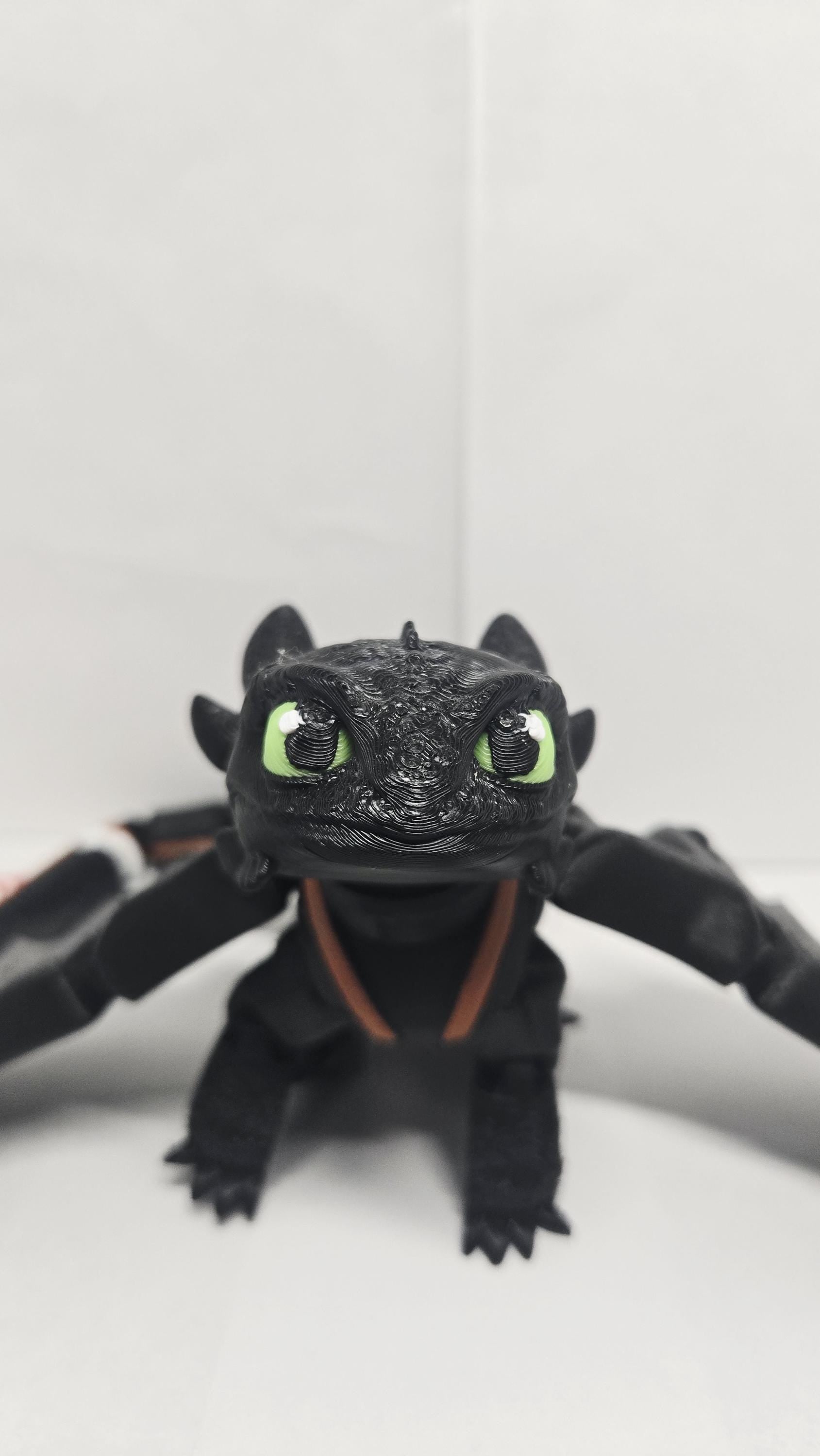 Straight front view of the articulated Toothless flexi figure highlighting his green eyes and head shape