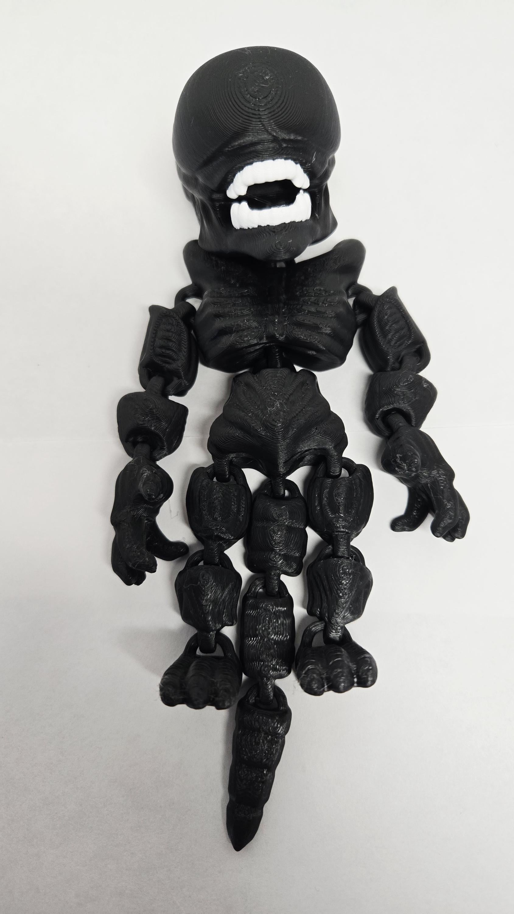 Straight front view of the articulated black Xenomorph flexi figure showing the detailed head shape and jointed limbs